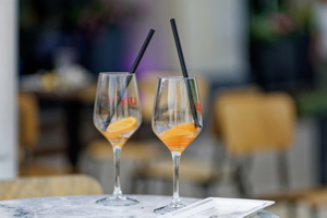 Glass of Aperol Spritz cocktail with a black straw